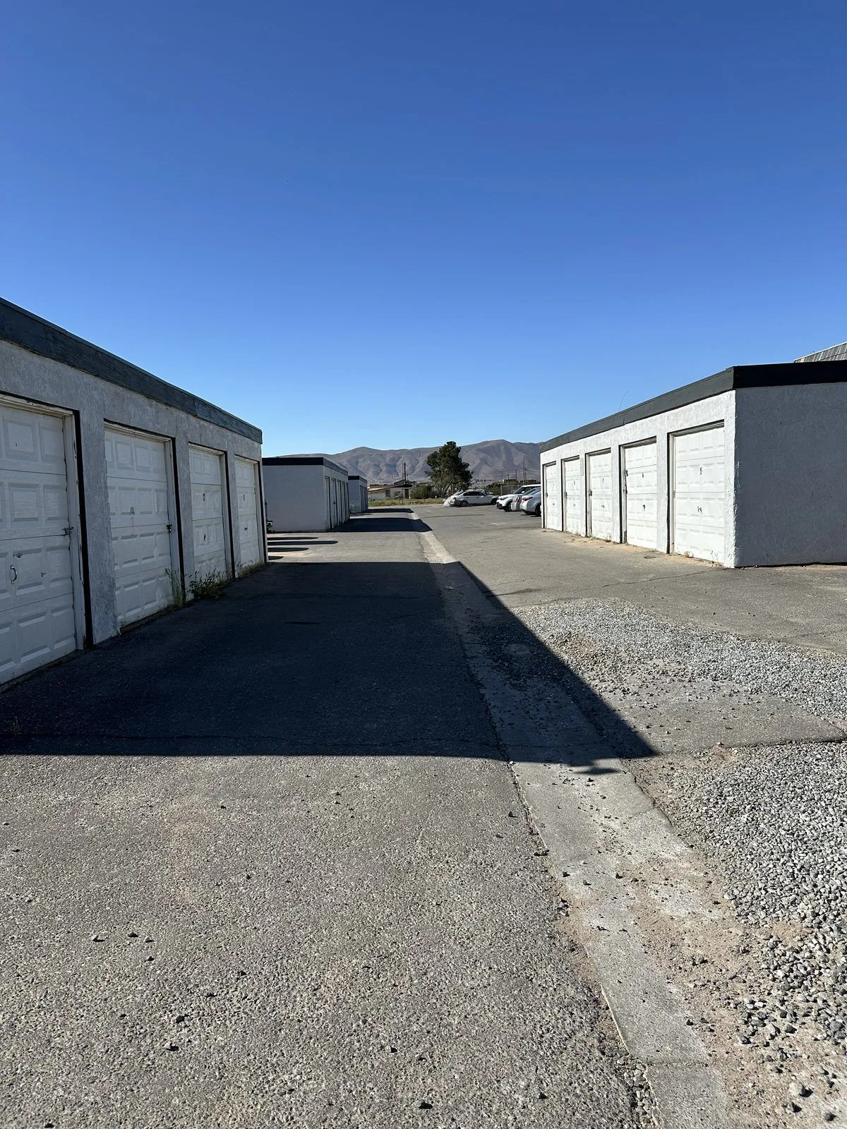 The row of private garages in the front lot, white overhead doors on a grey block building, with the townhomes and mountains beyond
