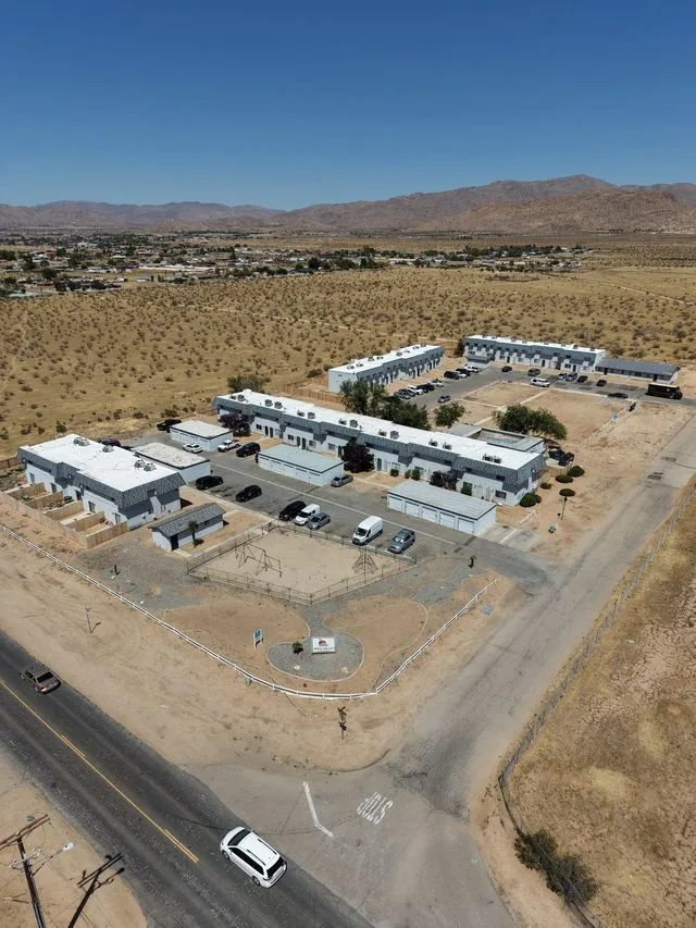 Aerial view looking north over the property toward the mountains, the town of Apple Valley spread across the desert floor behind