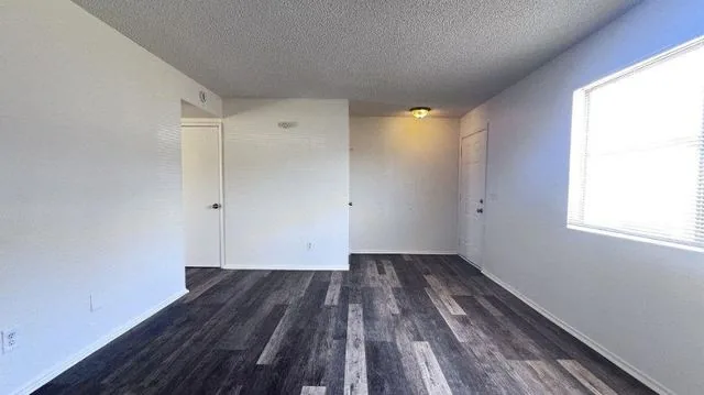 An empty room in a renovated townhome with grey plank flooring, white walls and a closet door